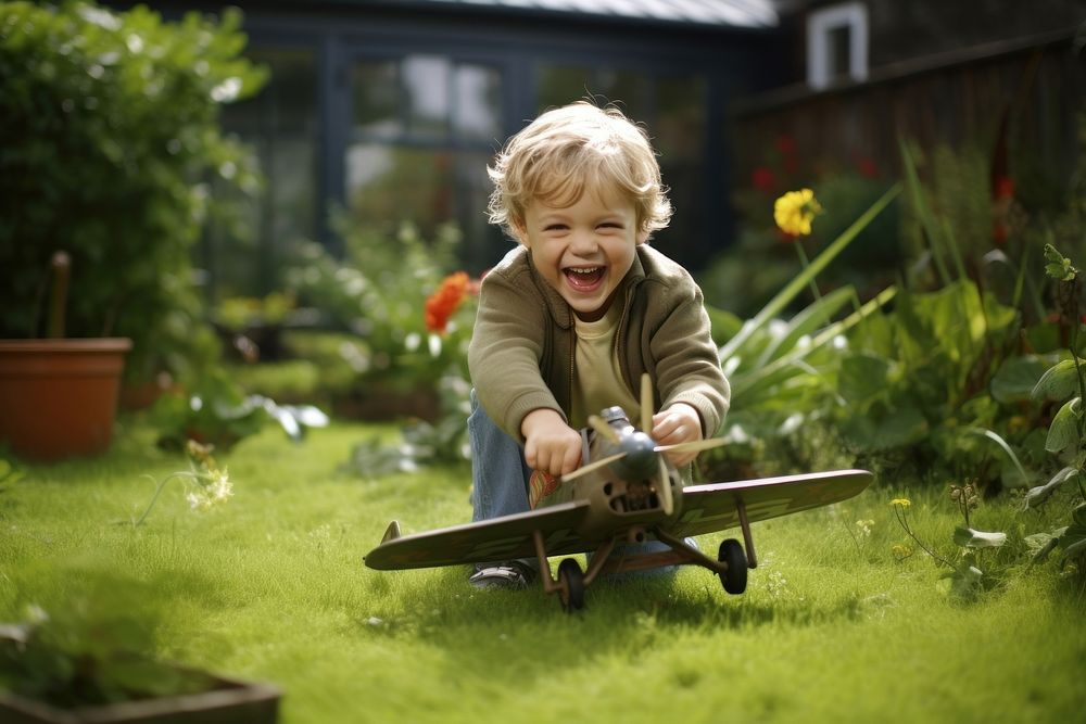 Smiling boy playing with toy airplane in garden outdoors smiling plant.