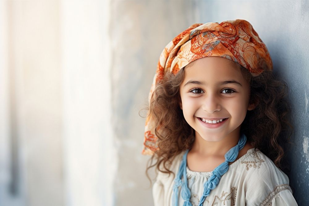 Middle eastern little girl in summer outfit smiling scarf smile.