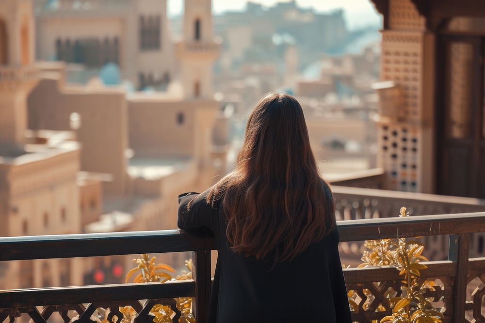 Saudi Arabian female tourist looking at old town architecture cityscape building.
