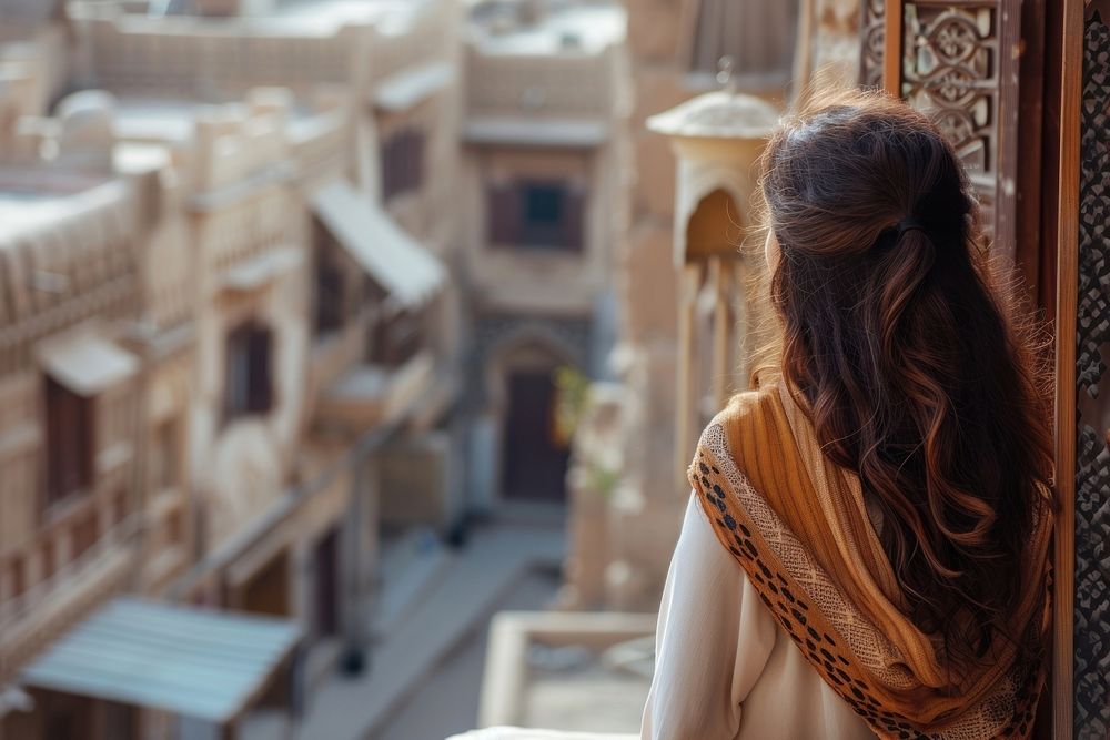 Saudi Arabian female tourist looking at old town architecture building adult.