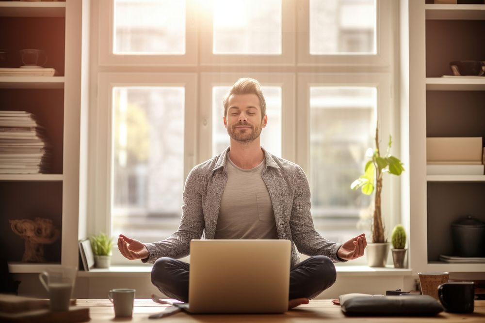 Man sitting on a yoga pose meditating computer laptop.