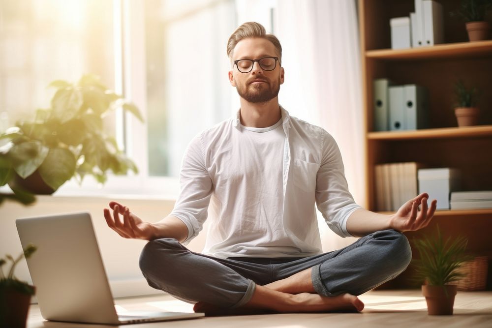 Man sitting on a yoga pose meditating computer laptop.