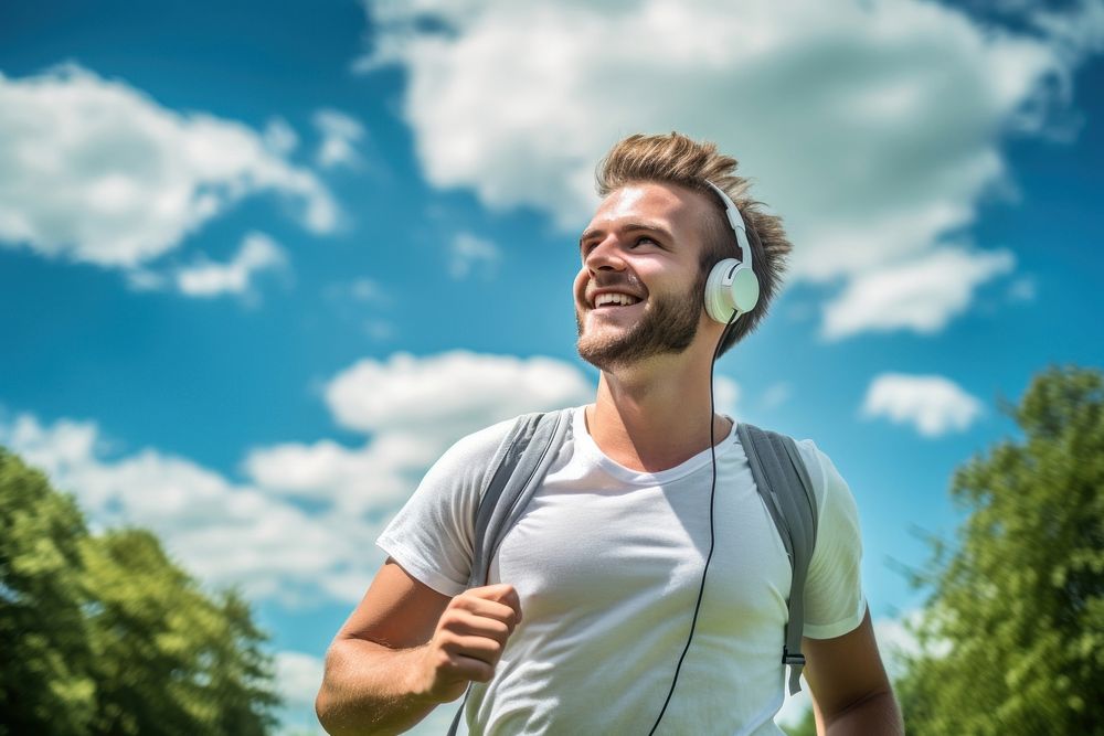 Young man jogging in a park headphones summer smile. AI generated Image by rawpixel.