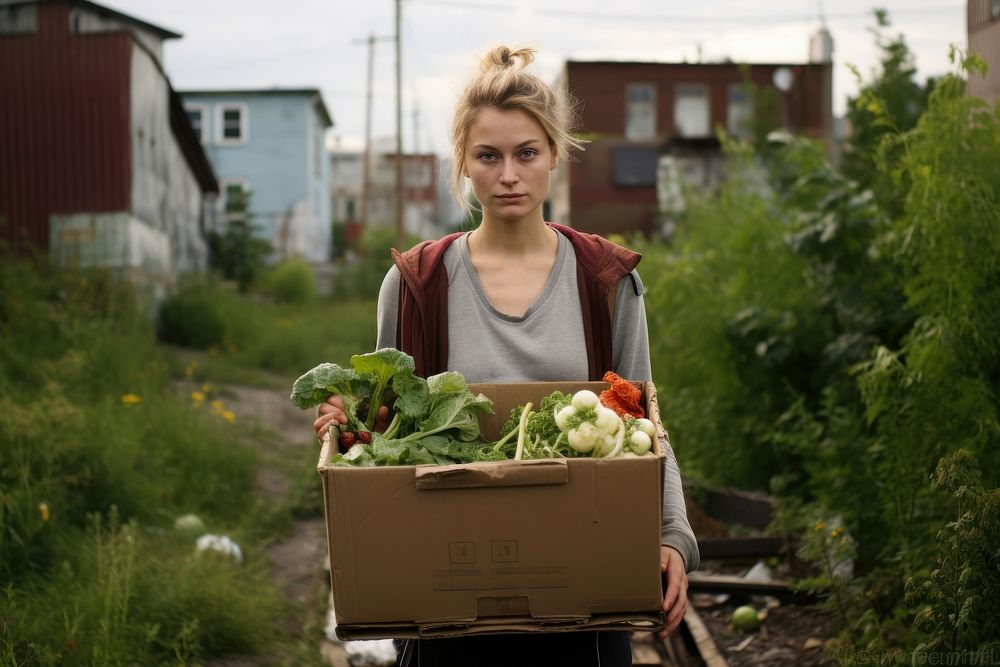Young woman carrying a box with vegetables gardening portrait outdoors.