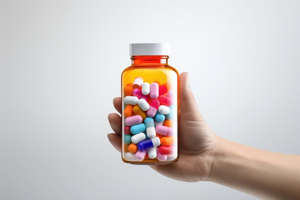 A hand holding a medicine bottle filled with colorful medicine capsules pill white background medication. AI generated Image…