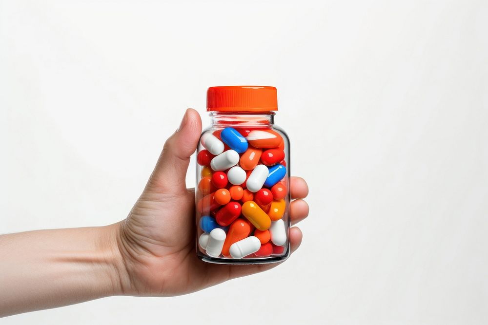A hand holding a medicine bottle filled with colorful medicine capsules pill white background medication. AI generated Image…