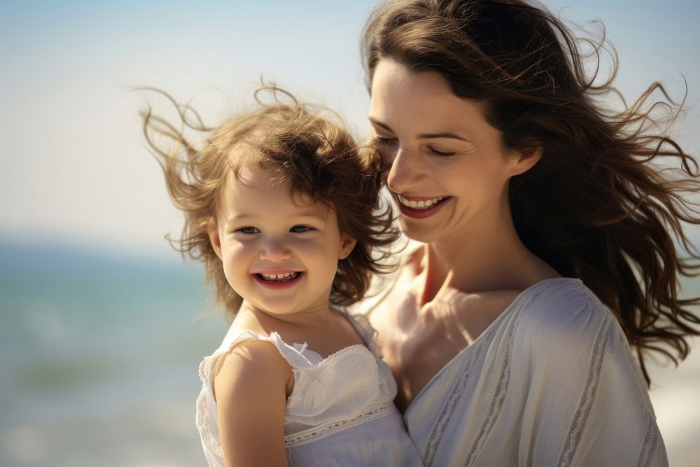 Mother carrying daughter laughing portrait outdoors.