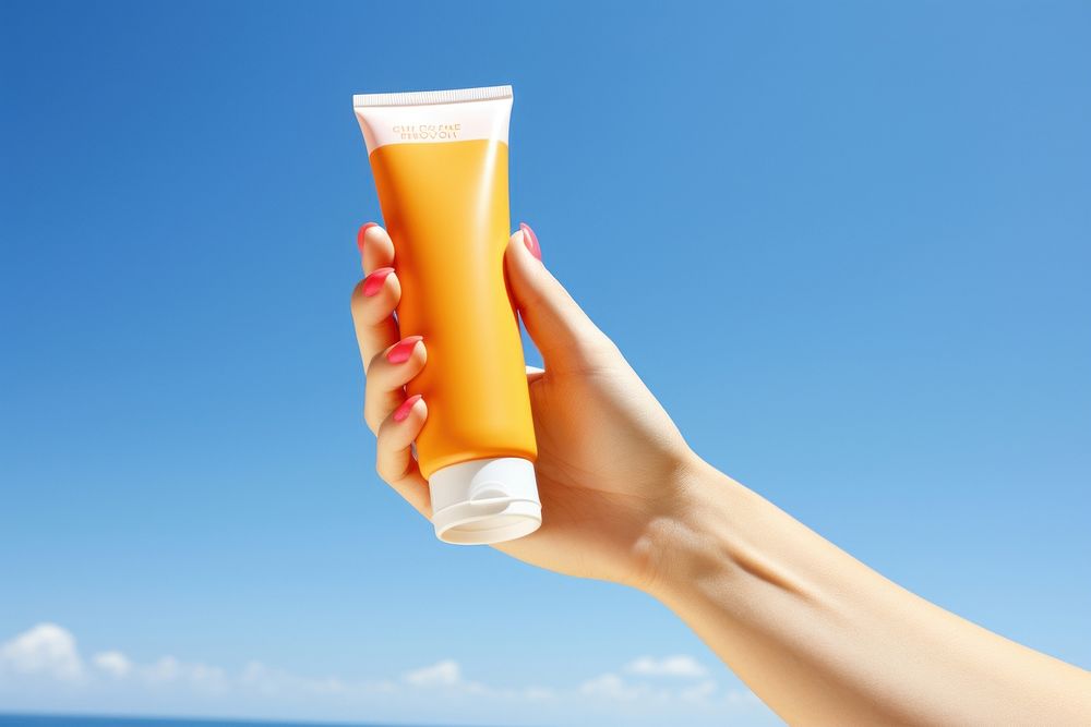 Hand holding sunscreen adult juice drink.