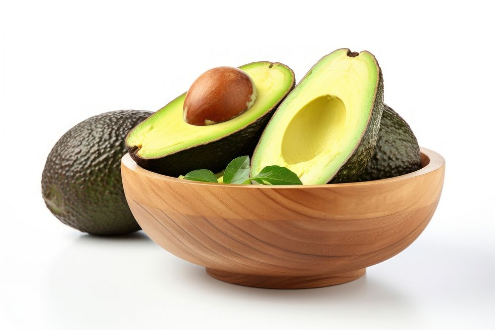 Guacamole in a wooden bowl and avocado fruits on the side plant food white background.