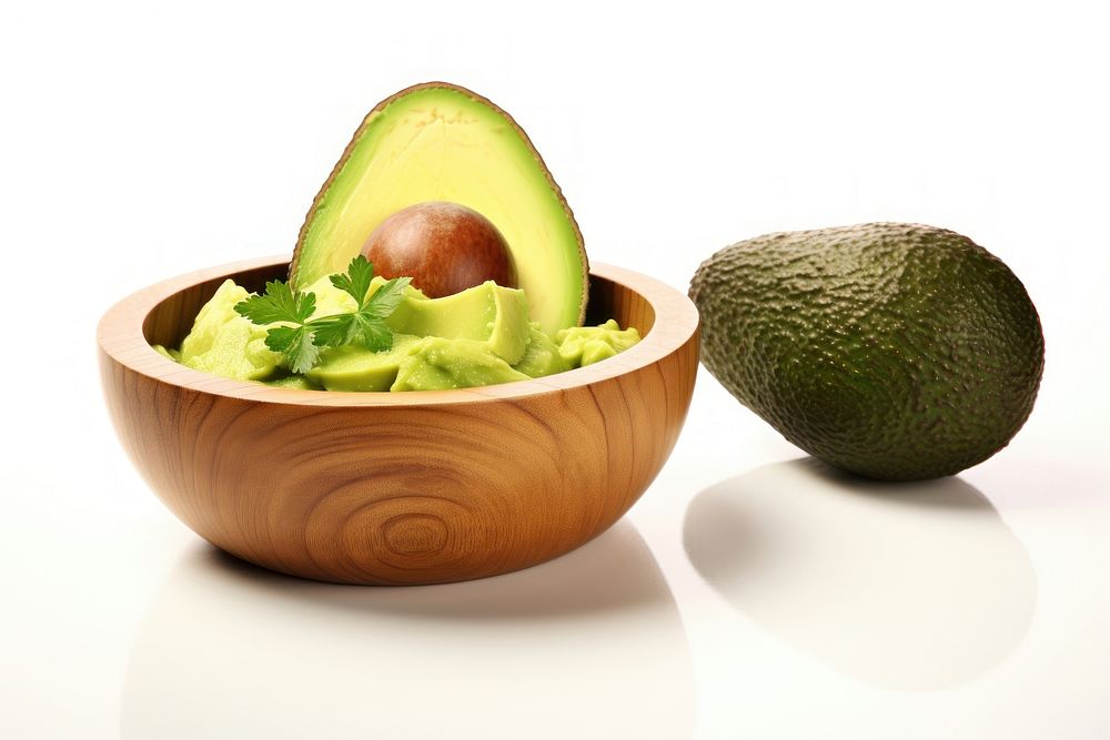 Guacamole in a wooden bowl and avocado fruits on the side plant food vegetable.