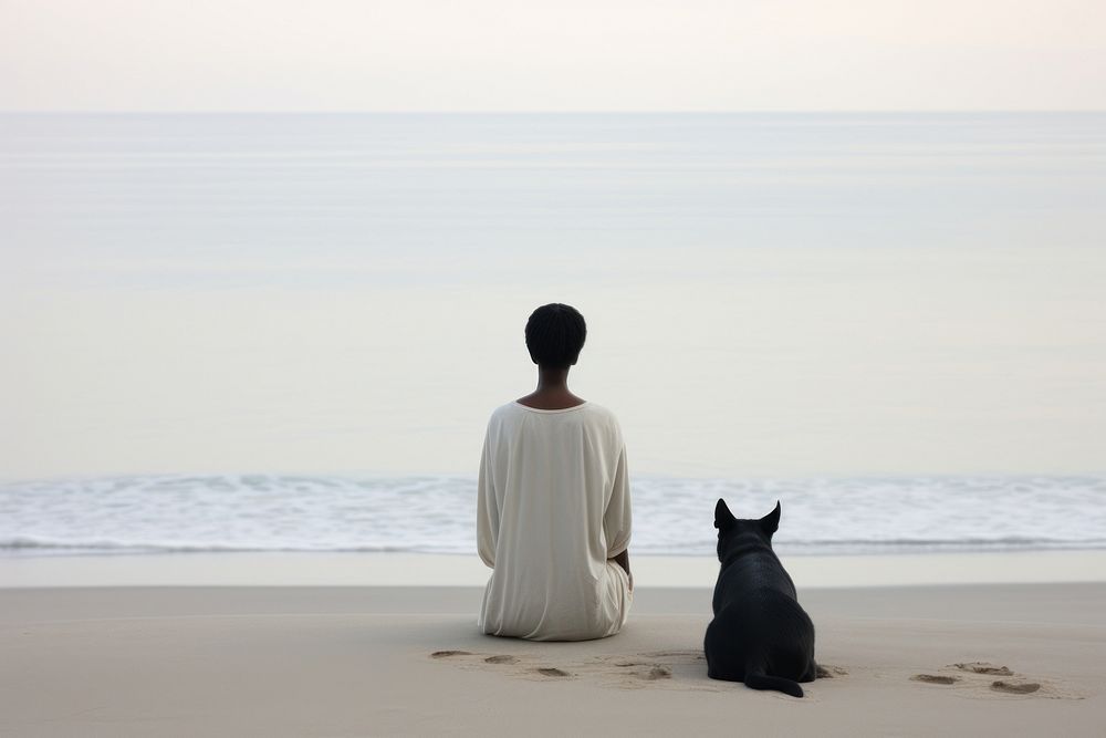 Woman and white dog sitting at beach silhouette portrait outdoors.