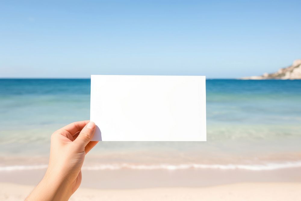 Hand holding blank name card beach outdoors nature.