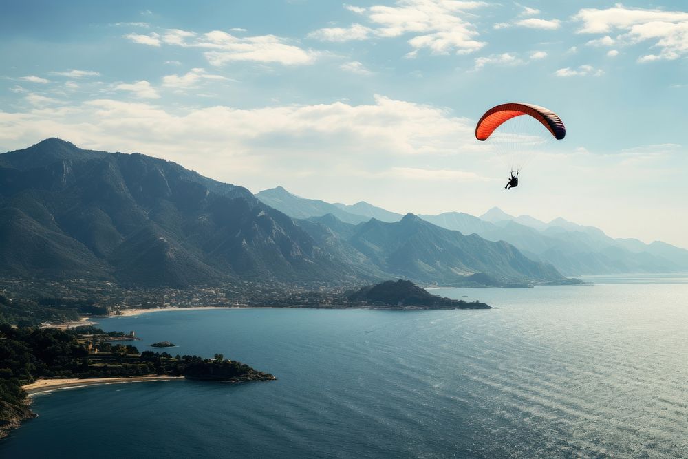 Paraglider flying over the sea with blue water and mountains paragliding recreation adventure. AI generated Image by…