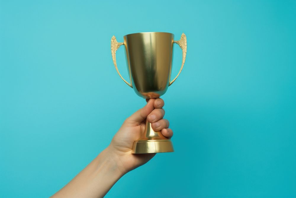 Gold trophy cup holding blue hand. AI generated Image by rawpixel.