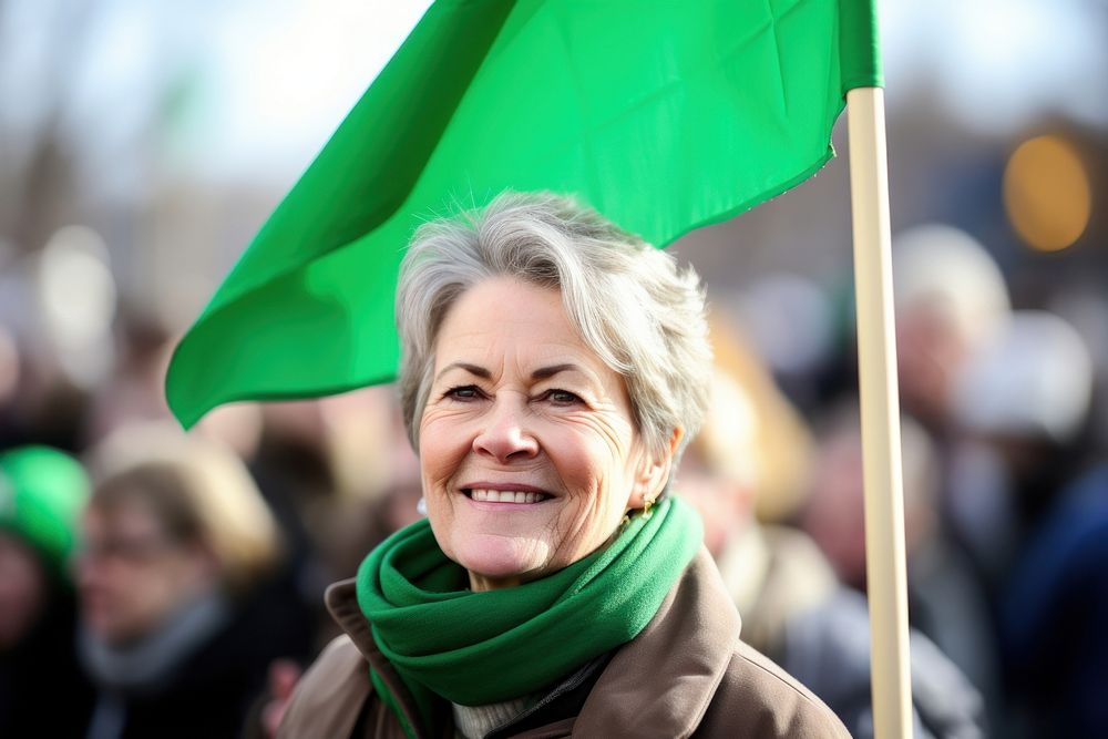 A middle-aged women holding a blank flag pole adult scarf smile.