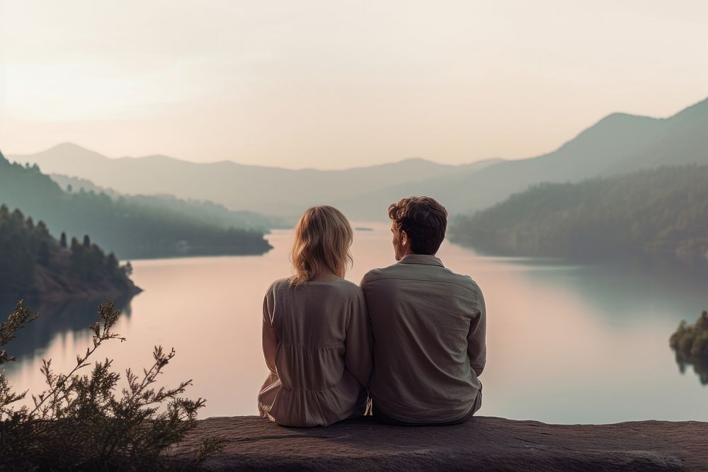 A couple sitting cutely on a mountain with lake background outdoors nature adult.