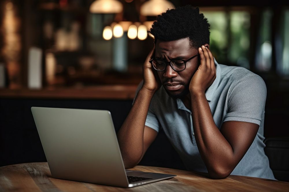 African man in glasses with upset laptop computer worried.