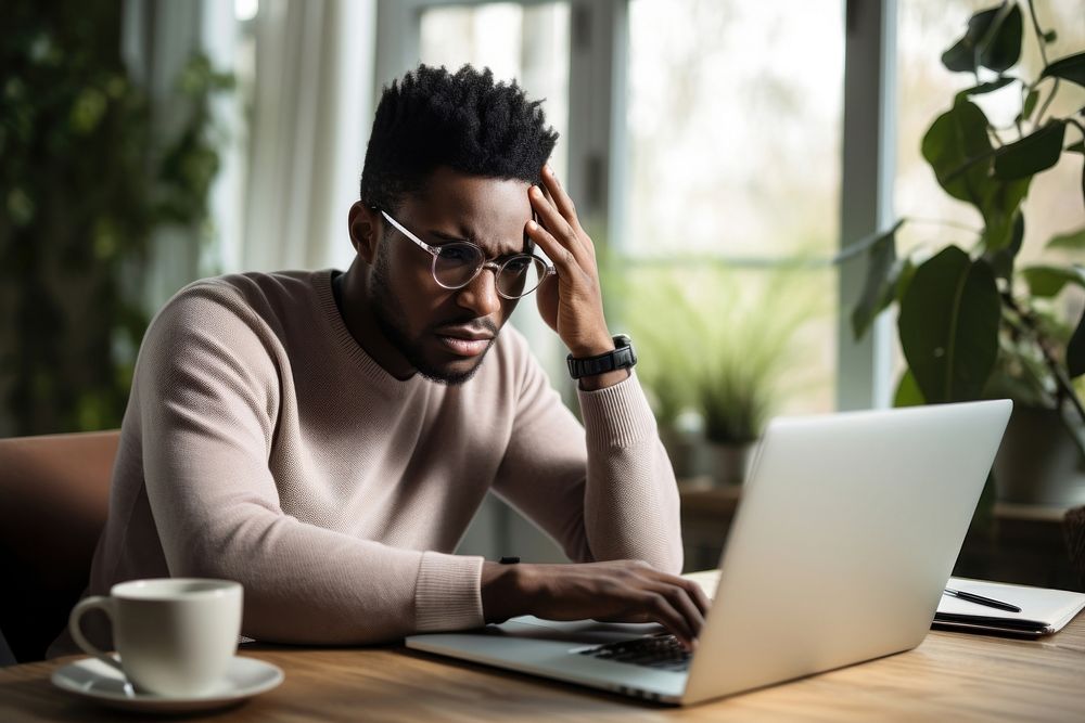 African man in glasses with upset laptop computer worried.