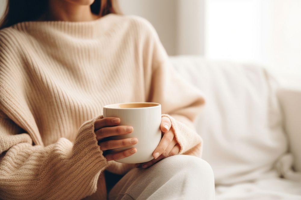 Woman holding a cup of tea sitting sweater coffee. 