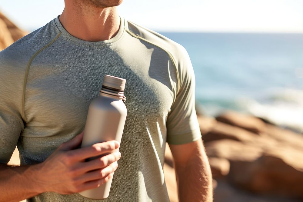 Man holding water bottle sports beach photo. AI generated Image by rawpixel.