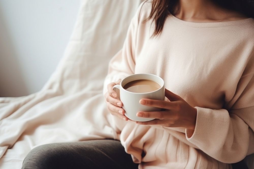 Woman holding a cup of tea sitting sweater coffee. AI generated Image by rawpixel.