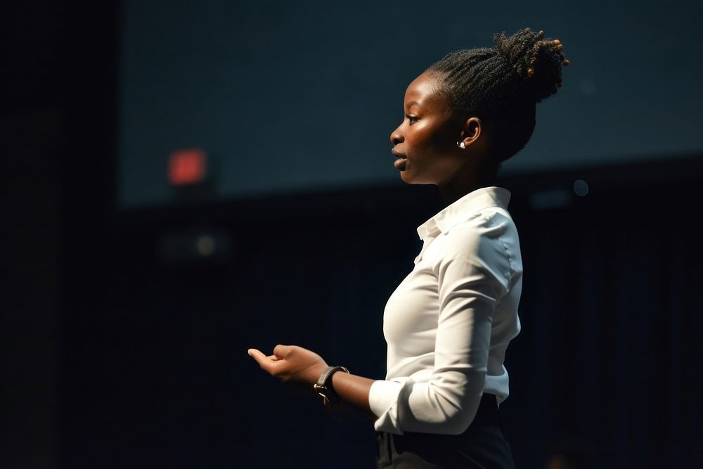 Black woman standing presenting project in conference hall performance hairstyle performer. AI generated Image by rawpixel.
