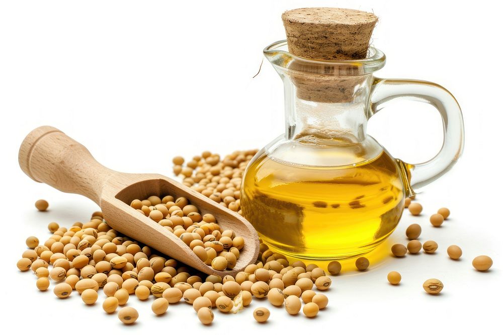 Soybean oil in glass jug with dry soy seeds in scoop on wooden table food white background refreshment.