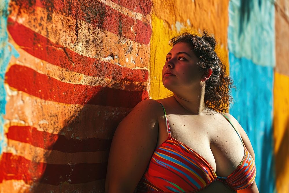 Chubby Latina woman in a swimming costume standing in front of a colorful wall swimwear portrait fashion. AI generated Image…