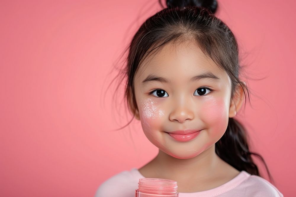 Little south east asian girls holding cosmetic product portrait child smile.