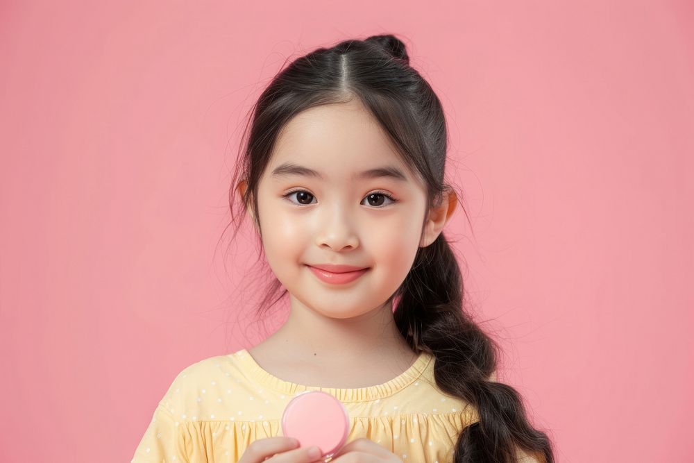 Little south east asian girls holding cosmetic product portrait child smile.
