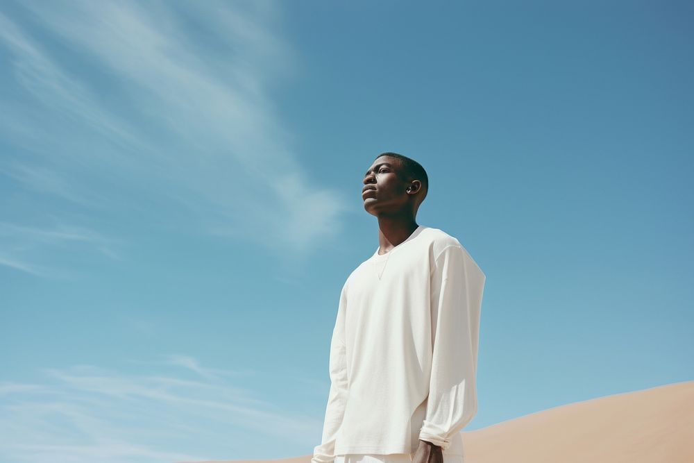African man in a minimal white standing outdoors desert.