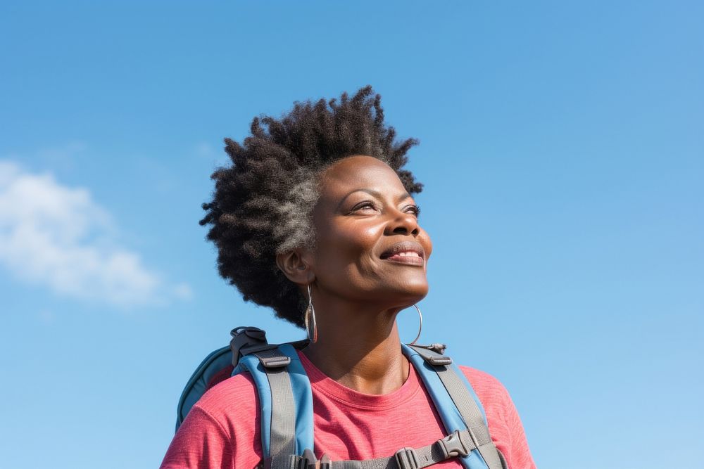 African middle age woman hiking backpack looking smile.