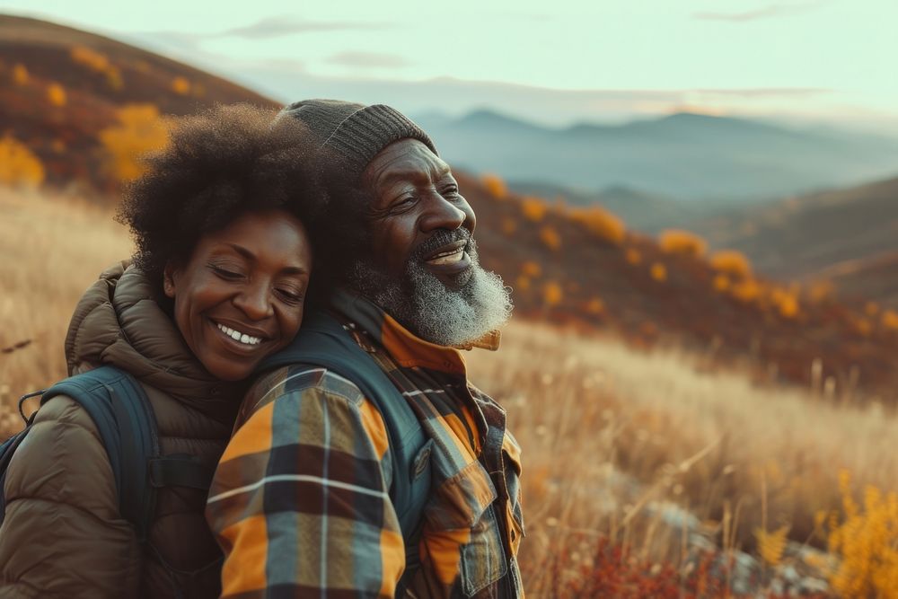 African middle age couple hiking mountain laughing outdoors.