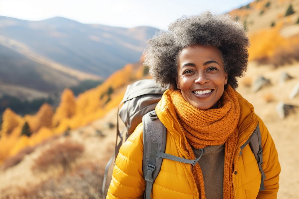 African middle age woman hiking backpacking mountain smiling.