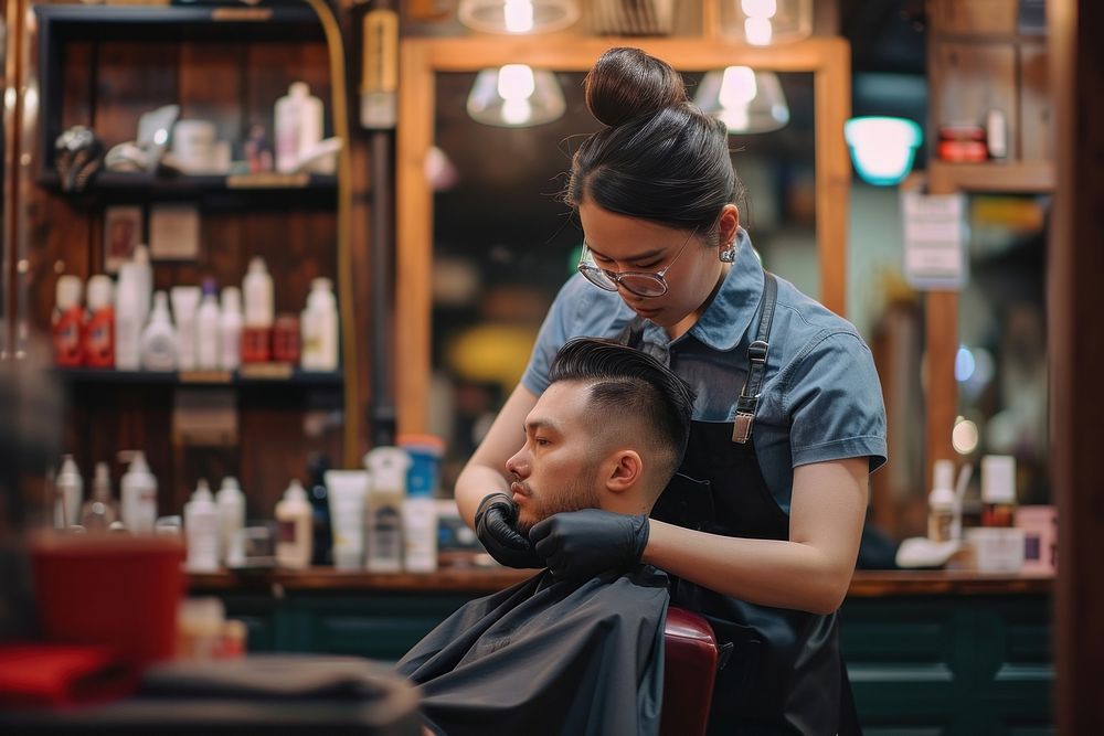 Woman barber and south east asian doing hair cut customer barbershop adult togetherness.