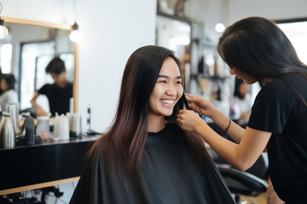 Smiling hairdresser doing haircut for south east asian woman adult electronics hairstyle.