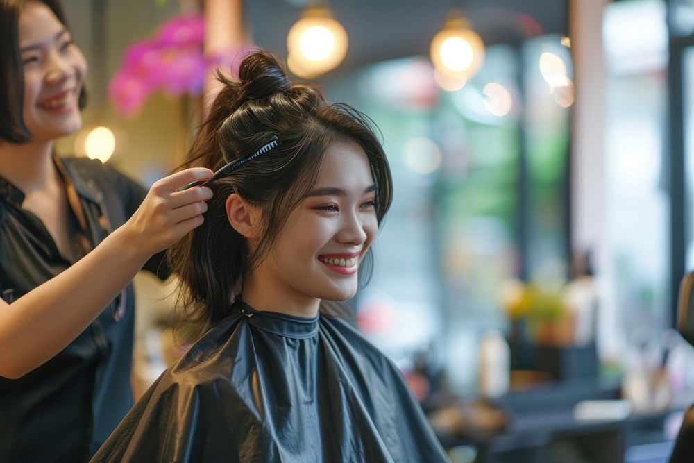 Smiling hairdresser doing haircut for south east asian woman adult hairstyle happiness.
