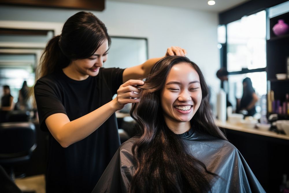 Smiling hairdresser doing haircut for south east asian woman adult togetherness hairstyle.