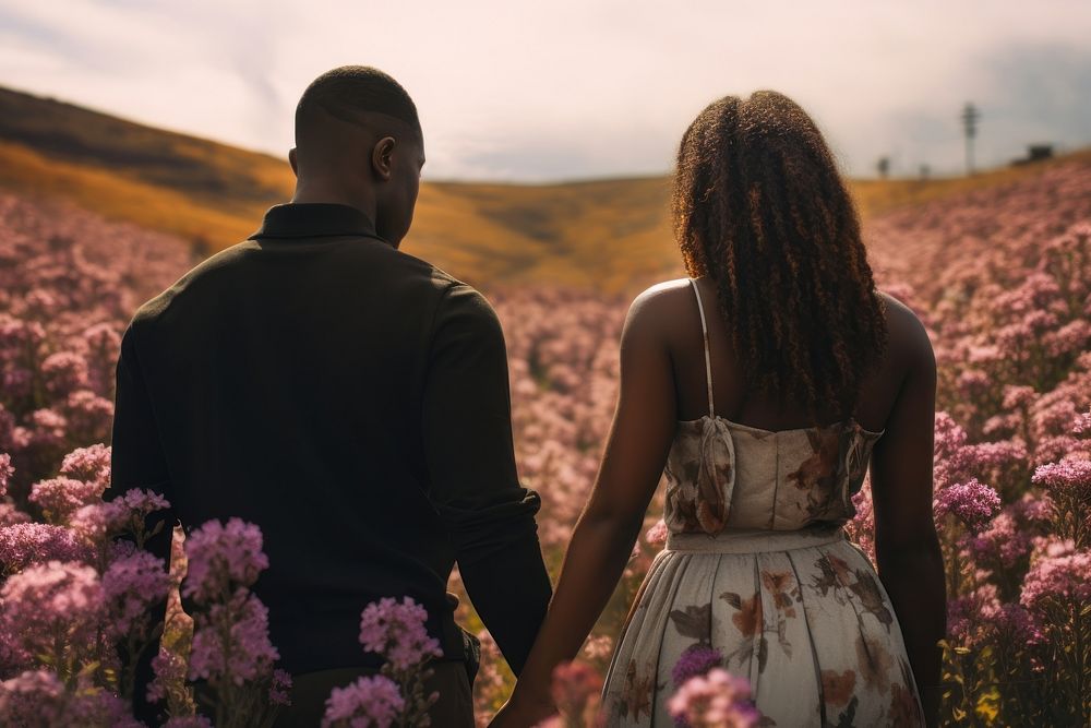 Black couple holding hands flower plant field.