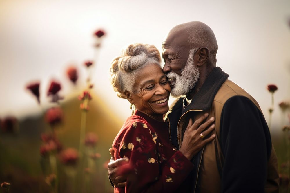 Black senior couple portrait outdoors hugging.