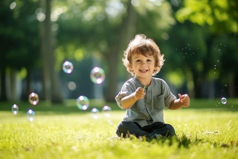 Boy blowing soap bubbles portrait outdoors grass. AI generated Image by rawpixel.