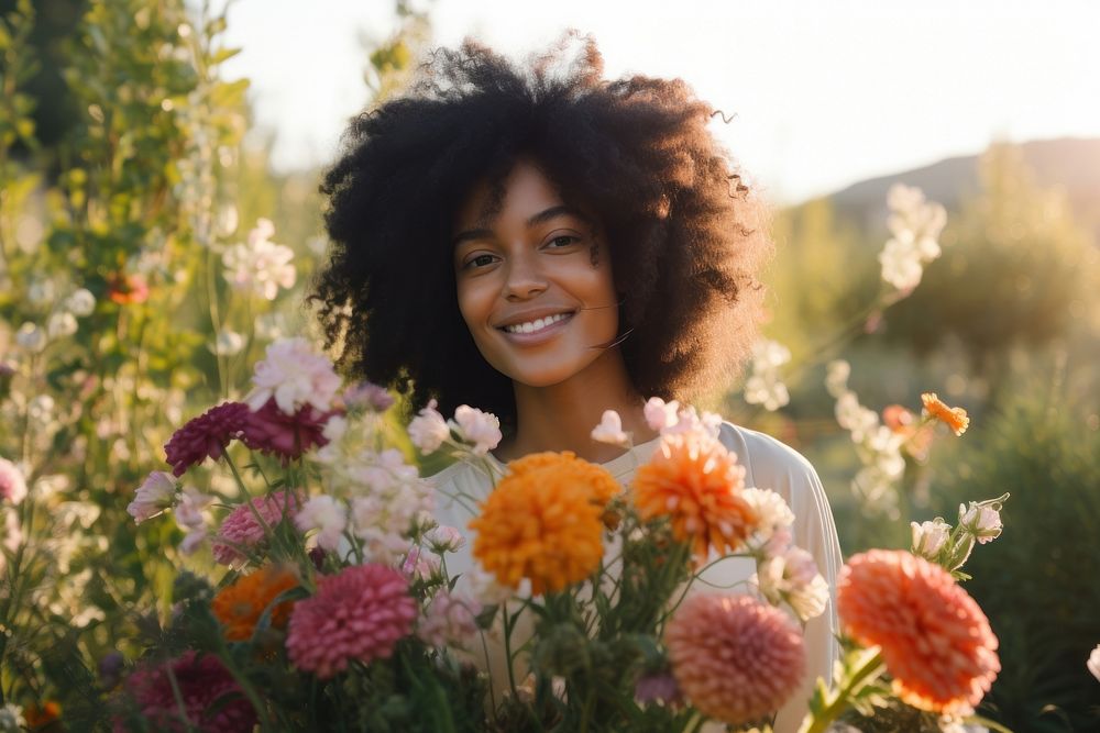 Black woman holding bouquet flower portrait outdoors smiling.