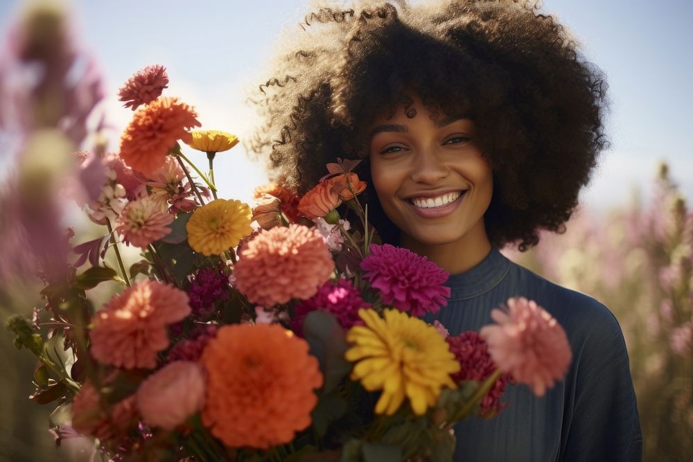 Black woman holding bouquet flower portrait outdoors smiling.