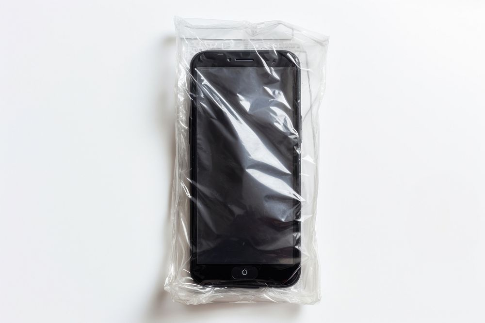 Plastic wrapping over a old mobile phone white background electronics technology.