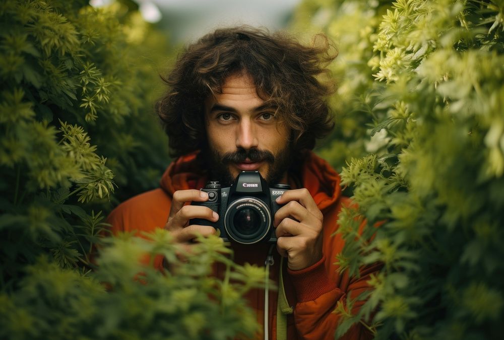 Man with a goofy hairstyle holds a camera portrait adult land. AI generated Image by rawpixel.