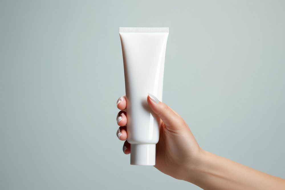  White cream tube cosmetics holding adult. AI generated Image by rawpixel.