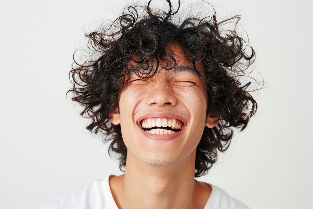 Asian man with white top laughing smile face curly hair.