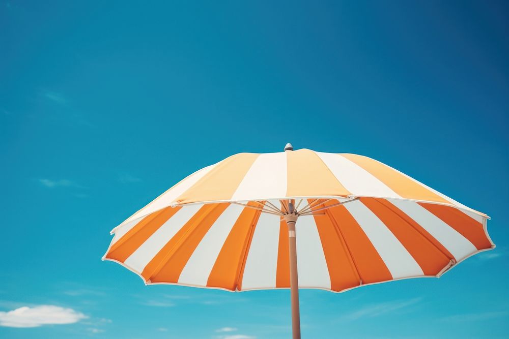 Orange and white striped umbrella against a blue sky yellow architecture tranquility. AI generated Image by rawpixel.
