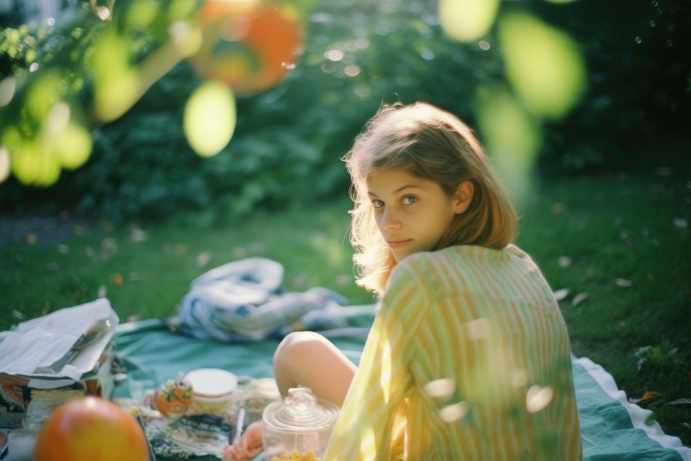 A teenage woman sitting picnic in the garden photography portrait plant. AI generated Image by rawpixel.