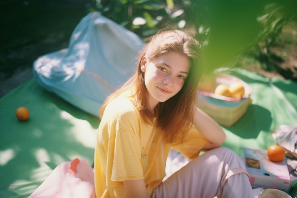 A teenage woman sitting picnic in the garden photography portrait outdoors. AI generated Image by rawpixel.